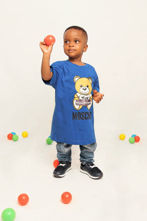 A young boy in a blue shirt holding balls