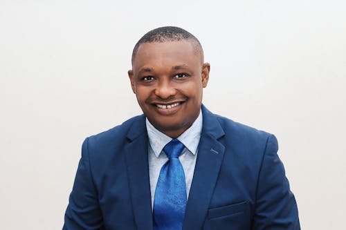 A man in a blue suit and tie smiling