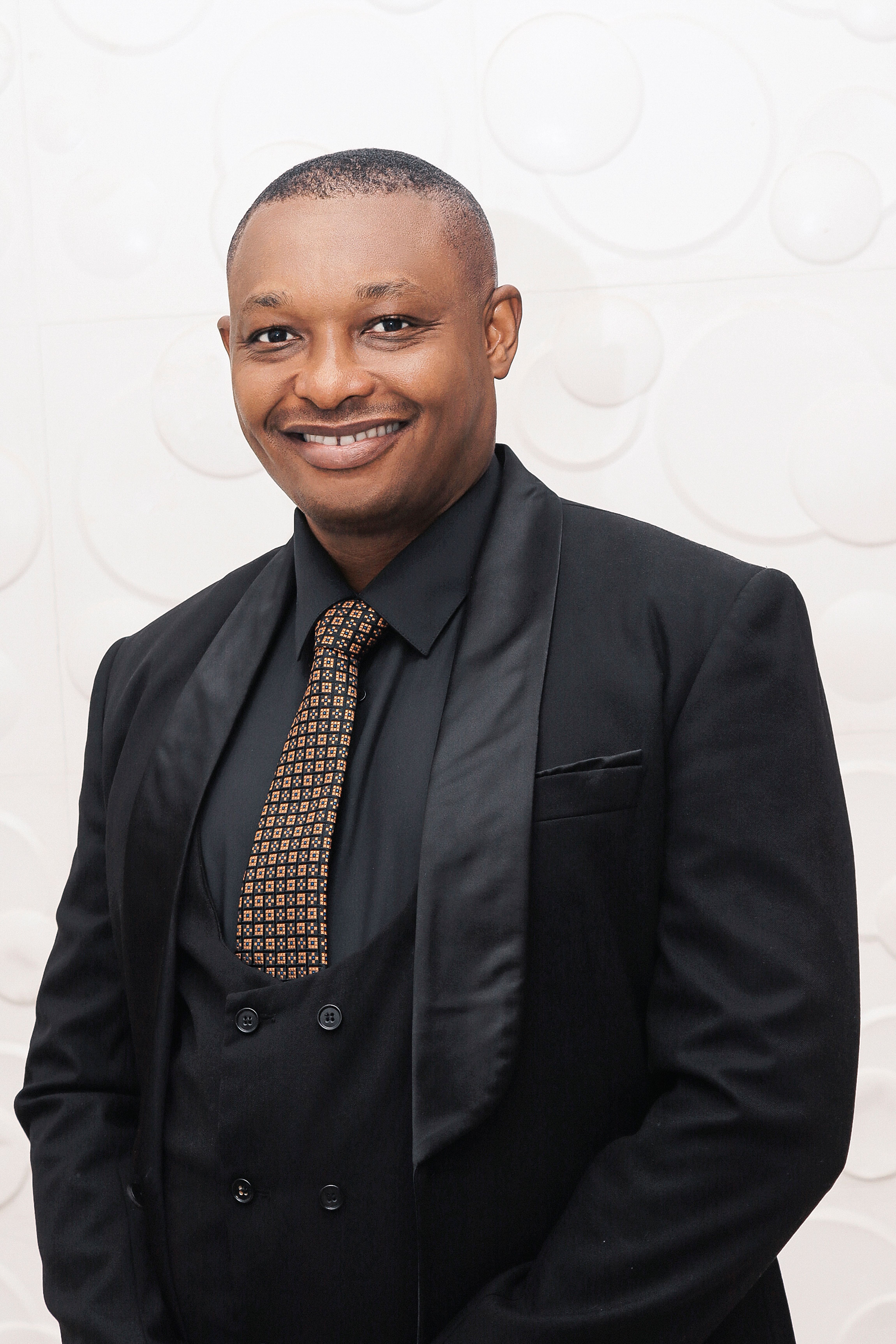 Elegant portrait of a well-dressed man smiling in a sleek black suit.