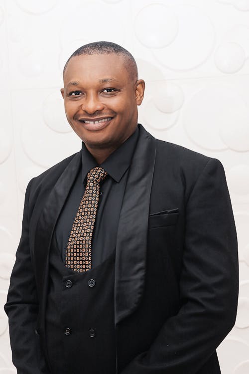 A man in a black suit and tie smiling