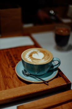 Latte art in a blue cup on a wooden tray in a cozy café setting, Baku.