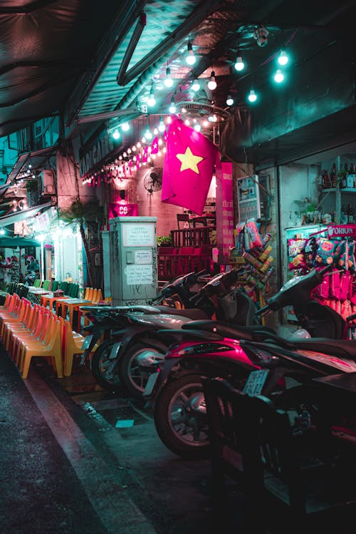 A street with motorcycles parked in front of a neon sign