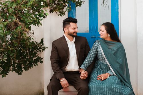 Free A charming outdoor portrait of an Indian couple sitting together holding hands, showcasing love and traditional attire. Stock Photo