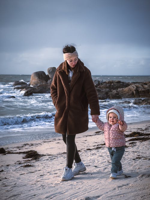 Free A Woman Walking on a Beach with Her Little Daughter  Stock Photo