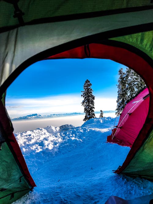 A tent is seen through a window looking out at the snow