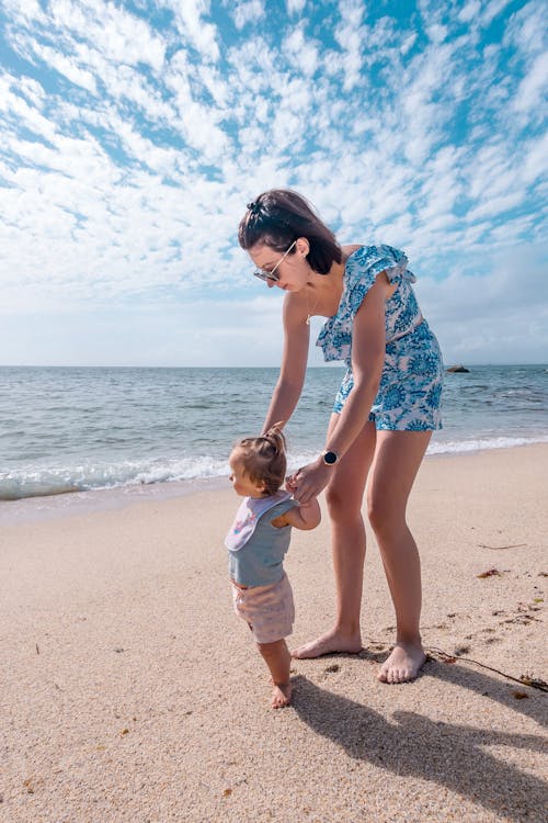 Free A woman and a child are standing on the beach Stock Photo