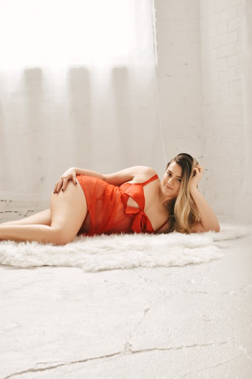 A woman in red lingerie laying on a white rug