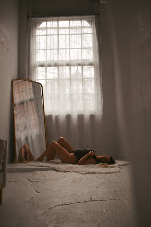 A woman laying on the floor in front of a mirror