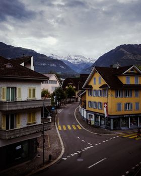 Idyllic Swiss street scene in a mountain village with traditional architecture and Alps backdrop.