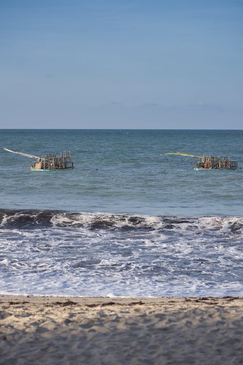 Two small boats in the ocean near a beach