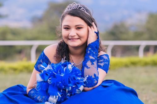 Free A young woman in a blue dress and tiara posing elegantly outdoors. Stock Photo