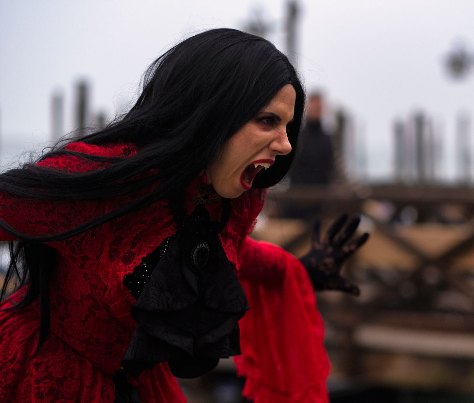 Woman in a vampire costume with black hair and red dress in Venice, Italy.
