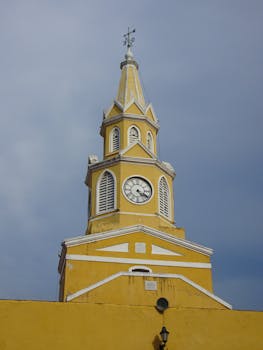 Discover the historic Torre del Reloj in Cartagena, an iconic landmark with its vibrant yellow facade.