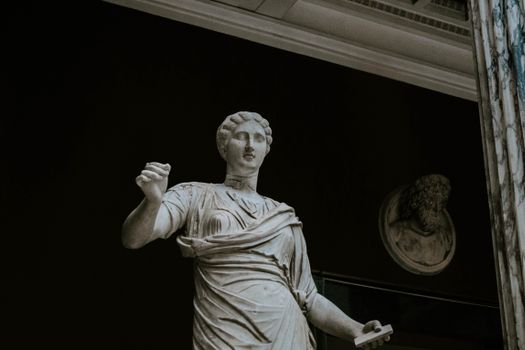 A classical marble statue showcased in a dimly lit museum gallery, emphasizing its timeless beauty.