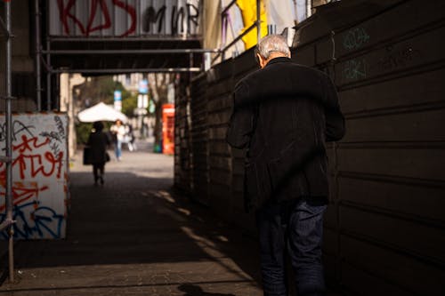 A man walking down a street with graffiti on the wall