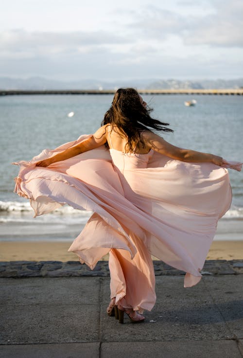 Brunette Woman Posing in Pink Dress on Sea Shore