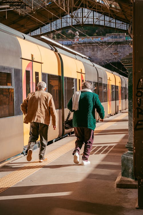 Two people walking on the platform of a train