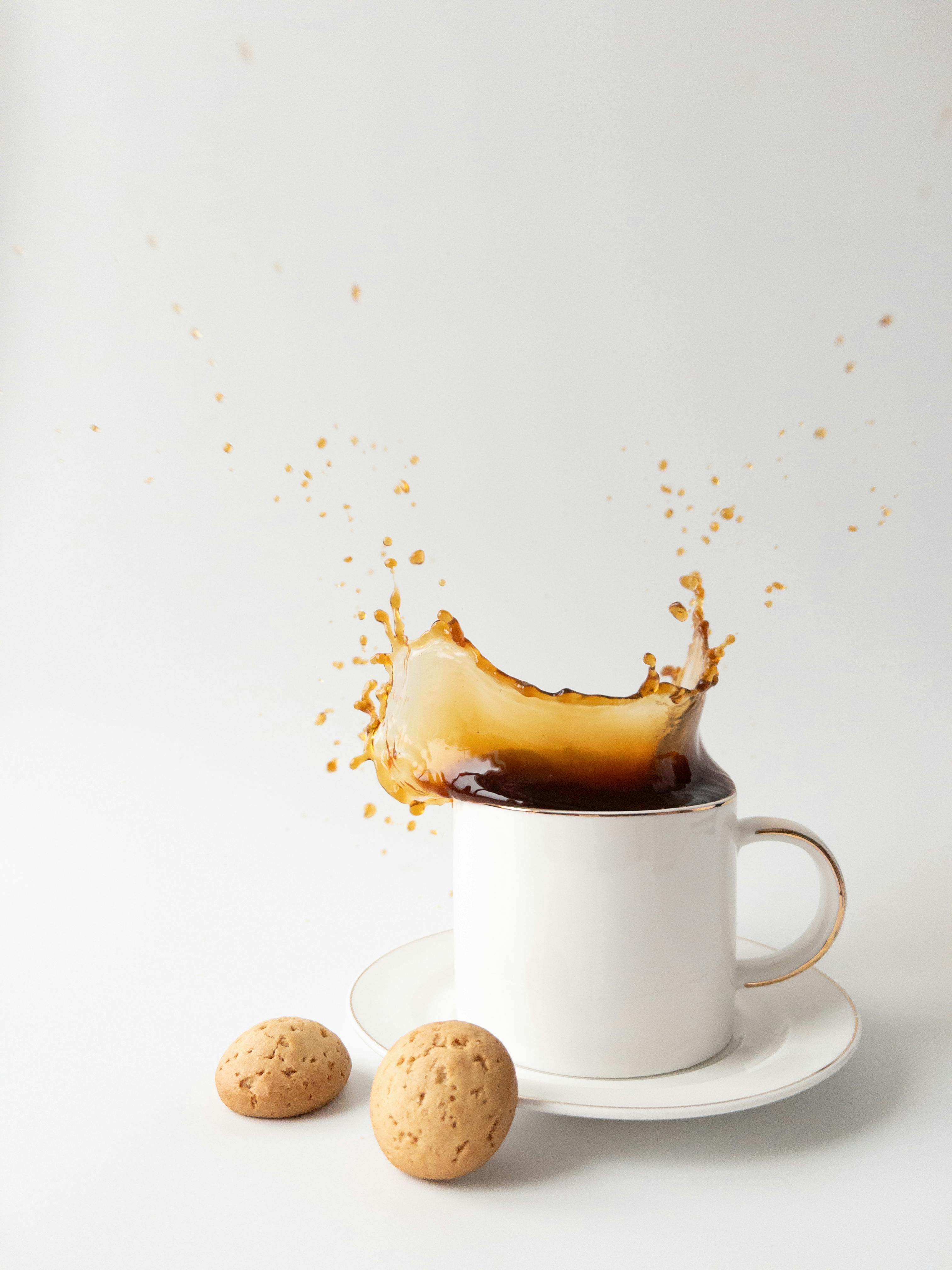 Dynamic shot of a coffee splash in a mug with cookies on the side.