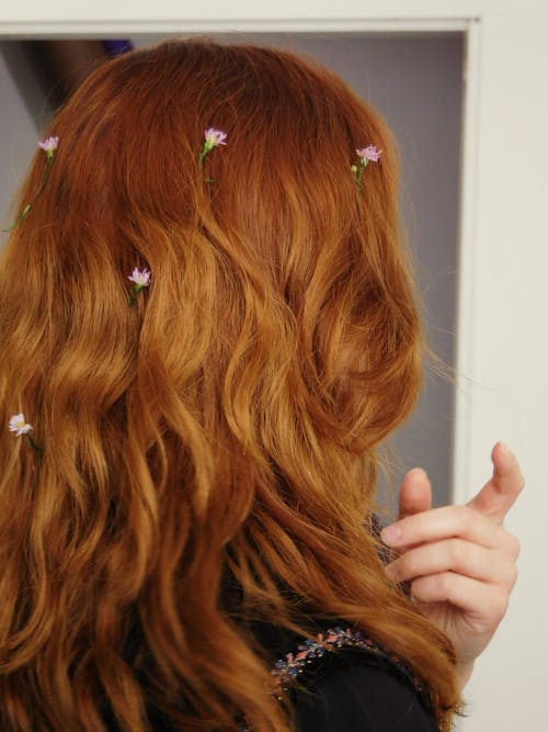 An orange-haired woman with flowers in her hair