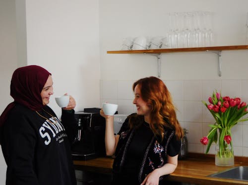 Two women are laughing while drinking coffee