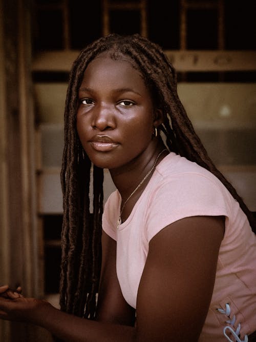A young woman with dreadlocks sitting on a bench