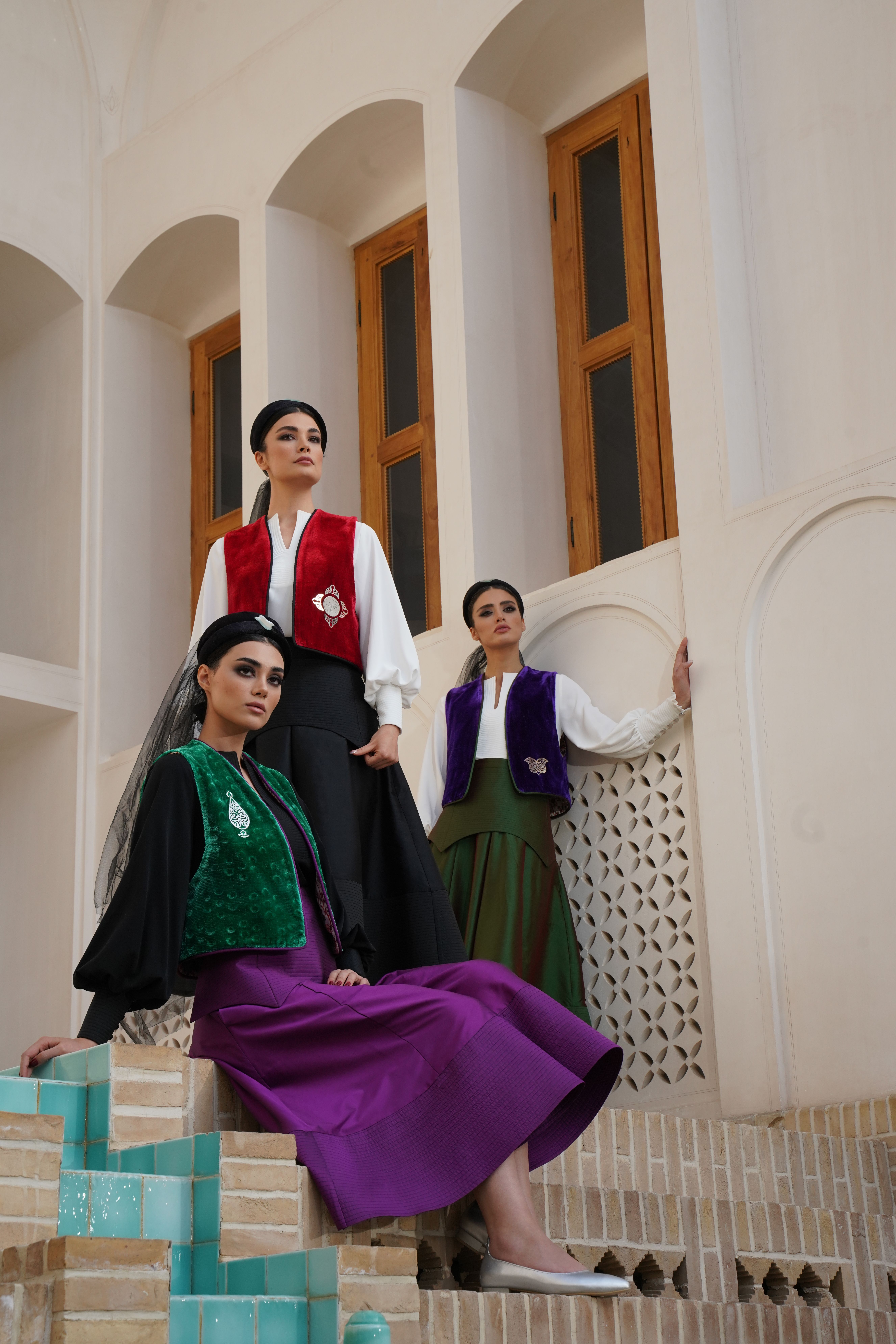 Stylish women in traditional attire posing on steps of historic architecture.