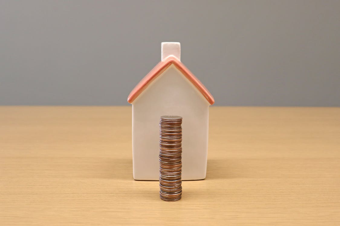 Free Stack of Coins in Front of a Porcelain House Stock Photo