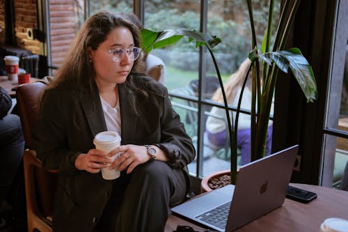 A woman in glasses sitting at a table with a laptop