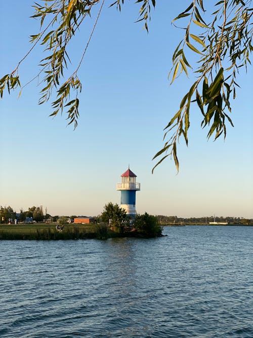 A lighthouse is on a body of water with trees