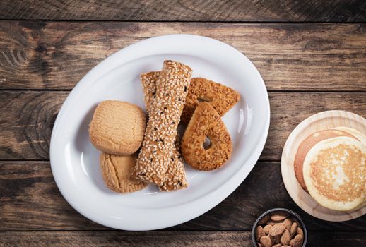 Close-up of various cookies, pancakes, and almonds on a rustic wooden table, ideal for food photography.