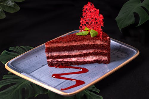 A piece of chocolate cake with red icing on a plate