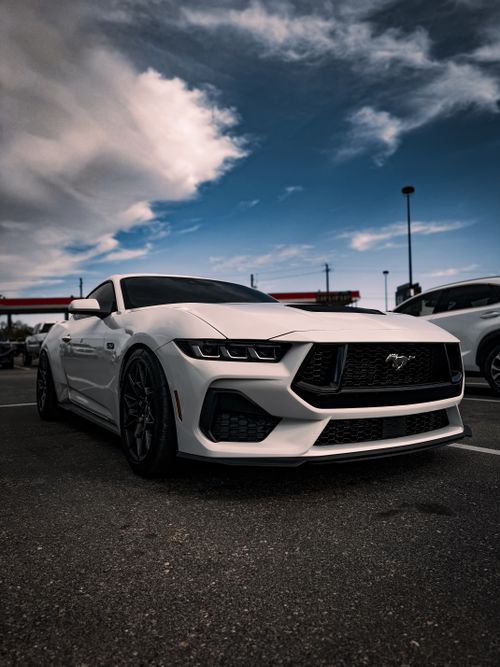Free Sleek white sports car parked in an urban lot under a dynamic sky, perfect for automobile enthusiasts. Stock Photo