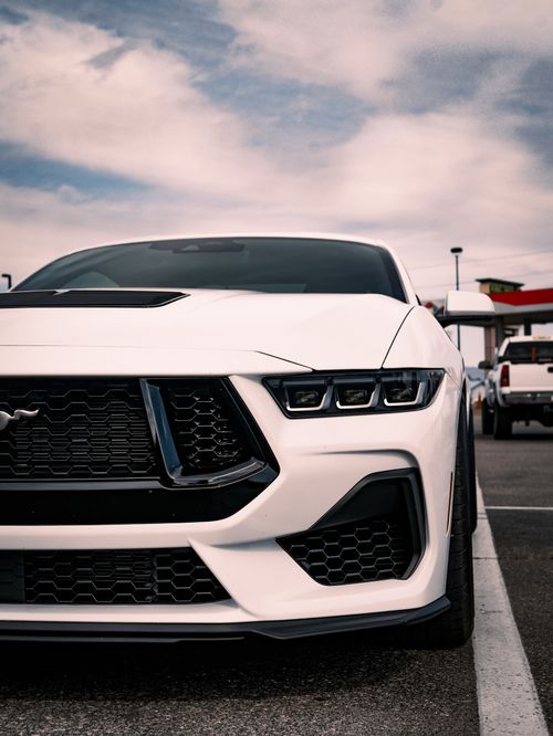 Free Close-up of a white sports car in a city parking lot, showcasing its sleek design. Stock Photo