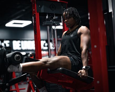 Muscular individual focusing on leg exercises in a gym setting, emphasizing strength and fitness.