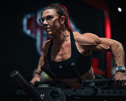 Focused woman in sportswear lifting weights in a gym environment.