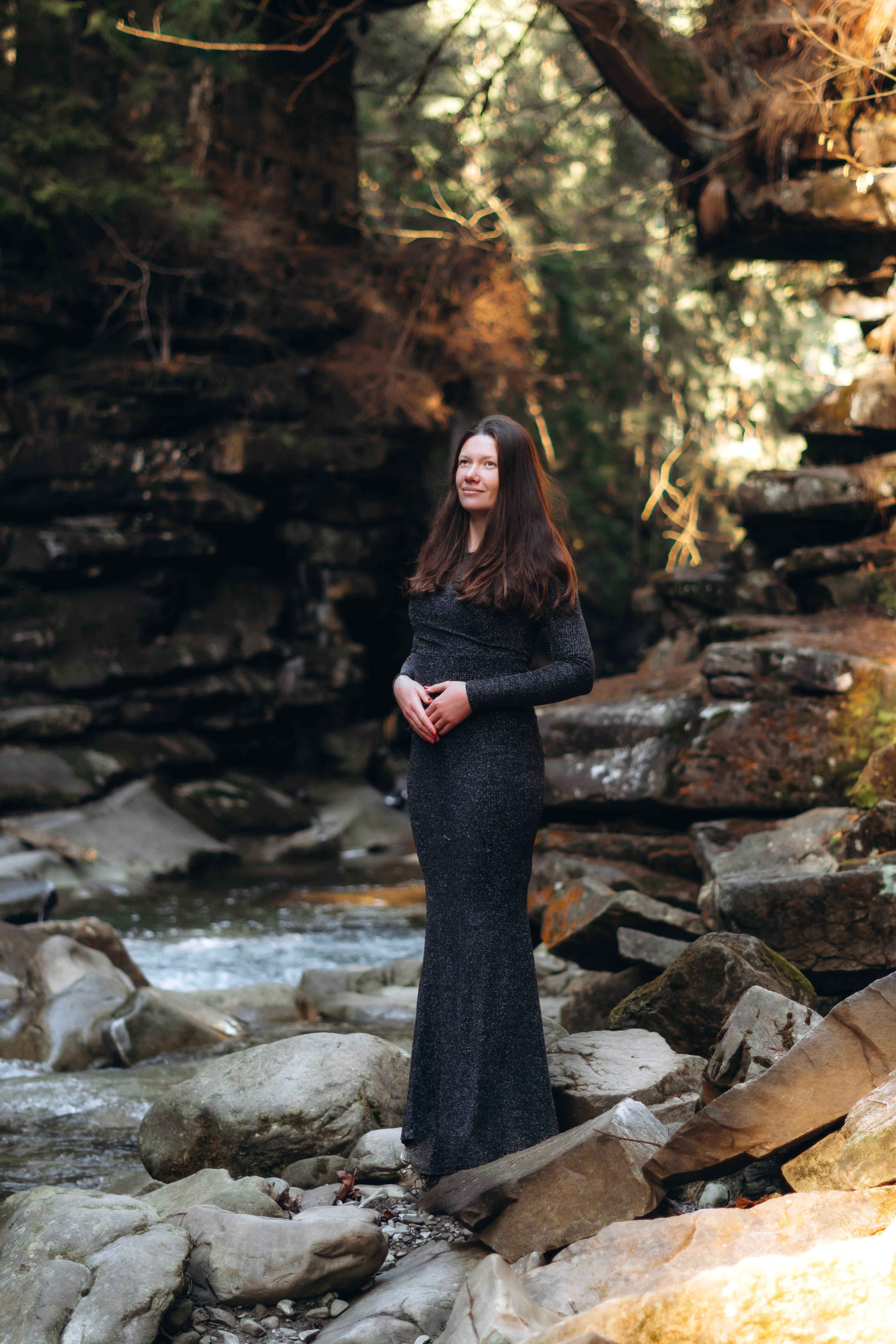 Woman in Black Dress Standing on Rocks by Stream · Free Stock Photo