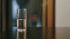 Close-up of a glass half-filled with water showcasing reflections in an indoor setting.