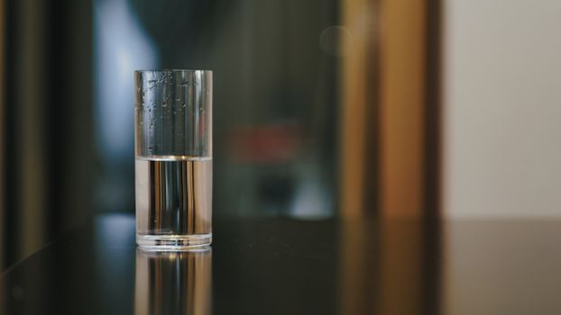 Close-up of a glass half-filled with water showcasing reflections in an indoor setting.