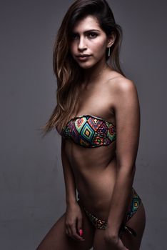 Portrait of a confident woman in a vibrant bikini posing in a studio setting.