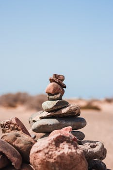 在阳光明媚的西班牙海滩上，艺术堆栈的石头保持着平衡
