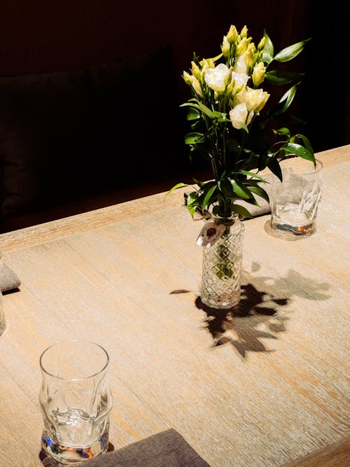 Glasses and Flowers Standing on a Table 