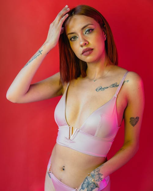A woman with tattoos and piercings in a pink bikini