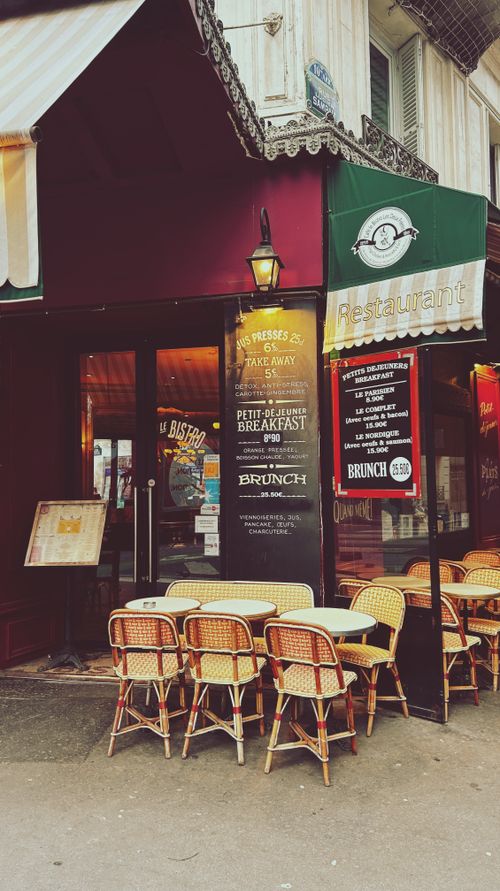 Free A cozy outdoor seating area at a Parisian bistro, showcasing classic French charm and dining atmosphere. Stock Photo