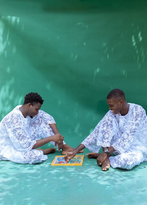 Two men sitting on the ground playing a game