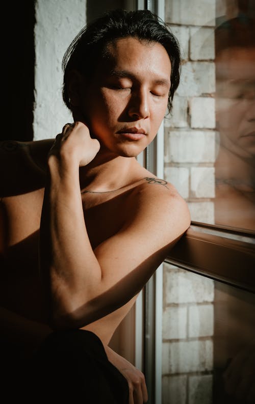 Portrait of a Shirtless Man next to a Window