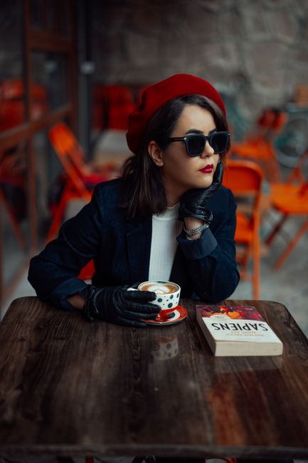 Elegant woman in a red beret sipping coffee in a Toronto café, embodying an urban chic style.
