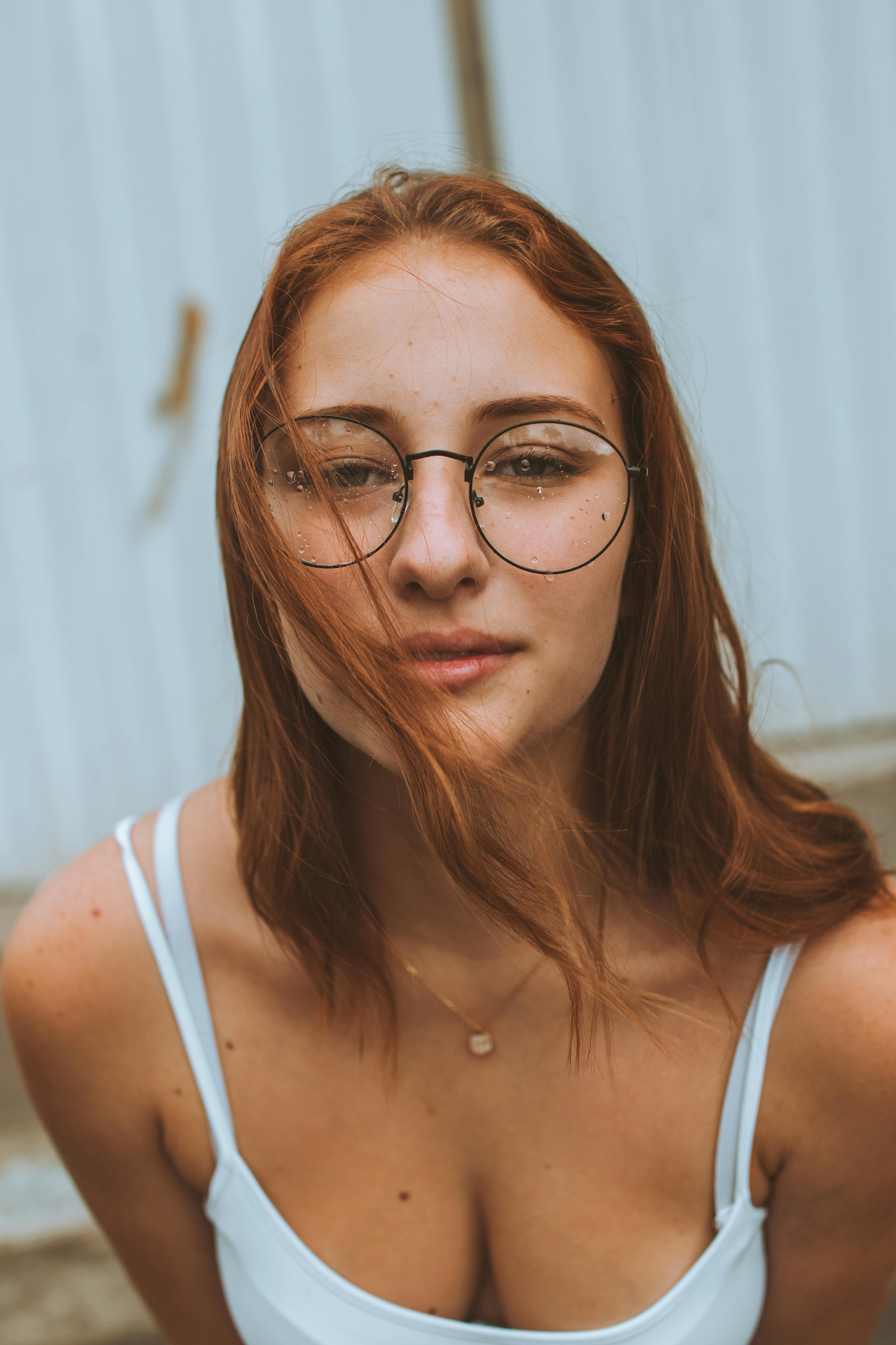 一位戴眼镜的红发年轻女子的特写肖像，时尚感十足