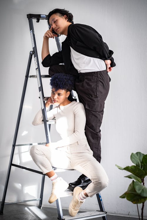 Woman and Man Sitting and Standing on Ladder