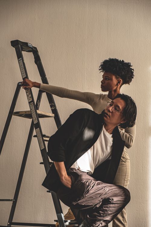 Free Stylish models posing with a ladder against a beige wall in Berlin. Stock Photo