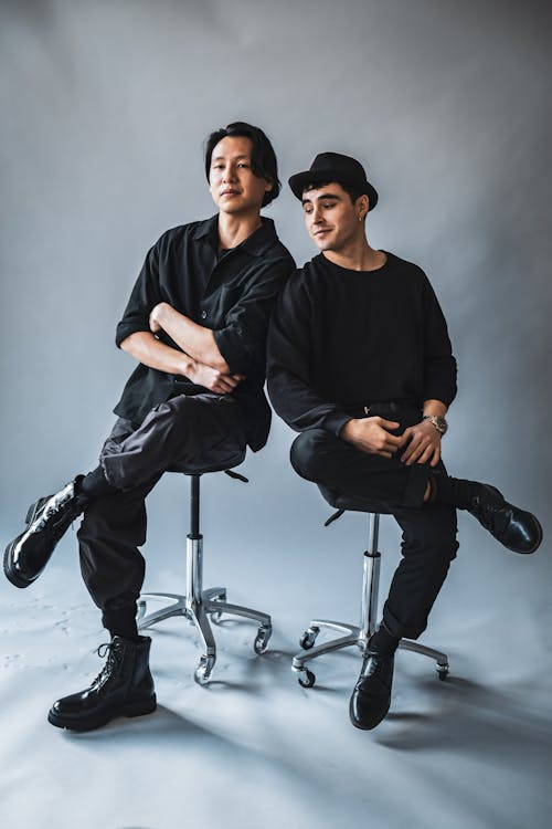 Two men in black clothing sitting on stools